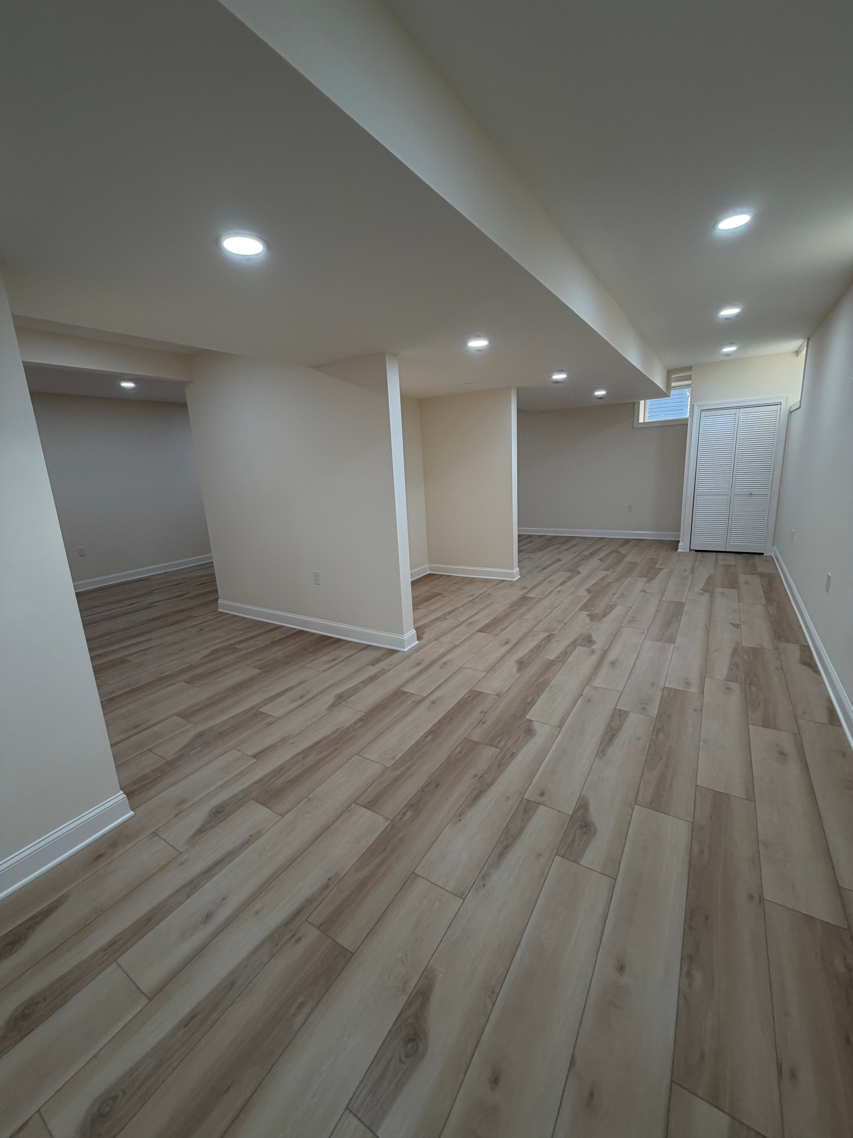 Finished basement staircase with wood-plank accent wall and recessed lighting
