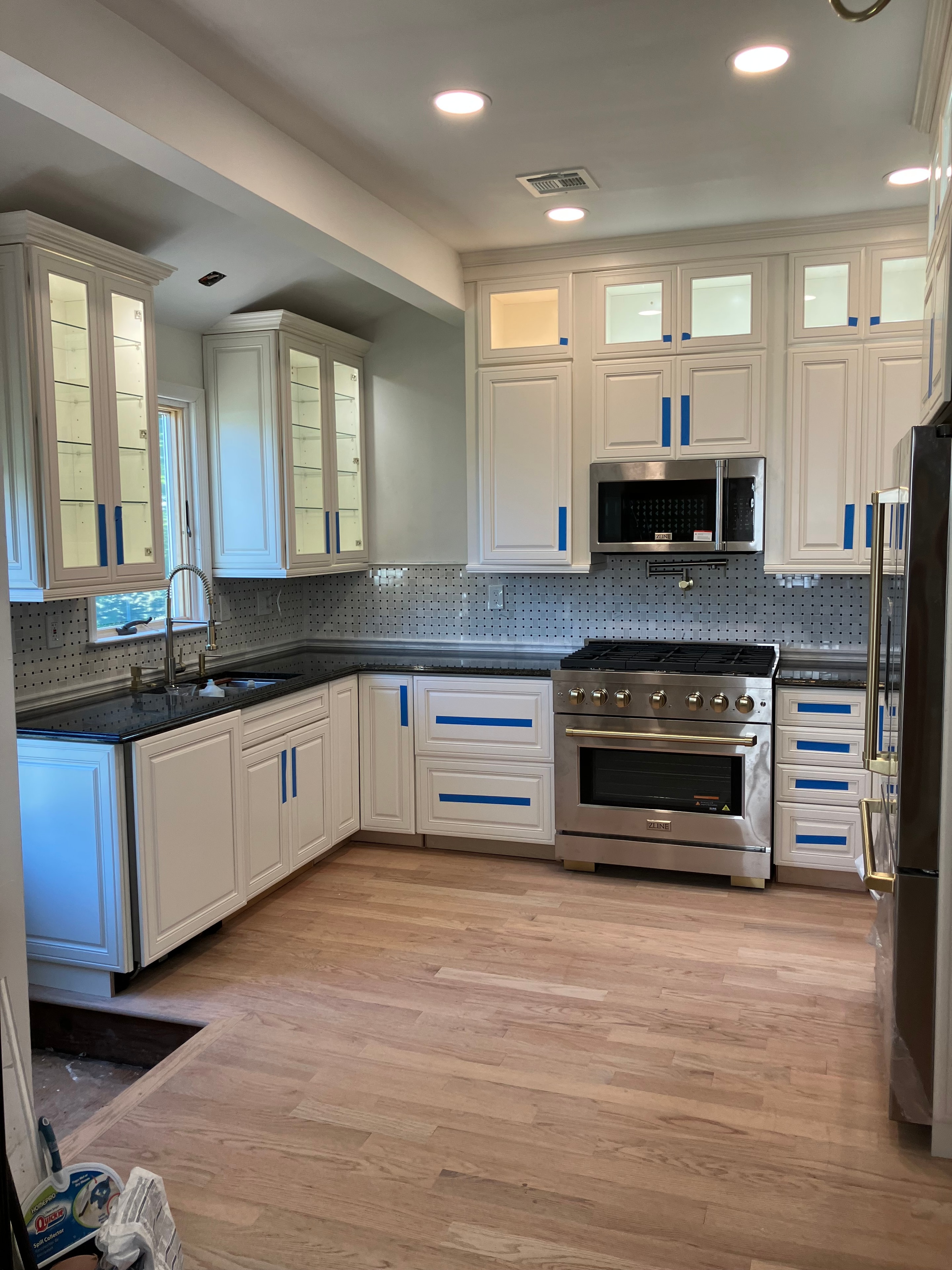 Large kitchen remodel with white cabinetry, professional range, and hardwood flooring in progress